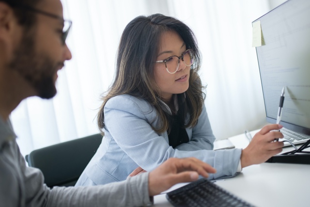 A person explaining data on a computer screen to another person