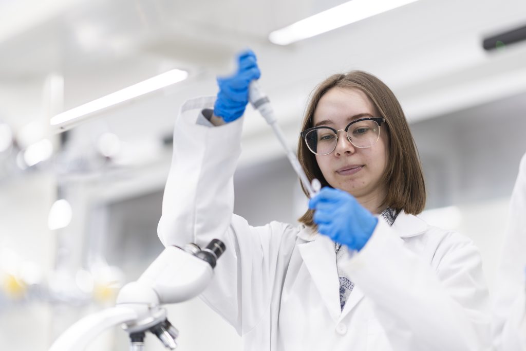 A scientist pipettes liquid into a test tube.